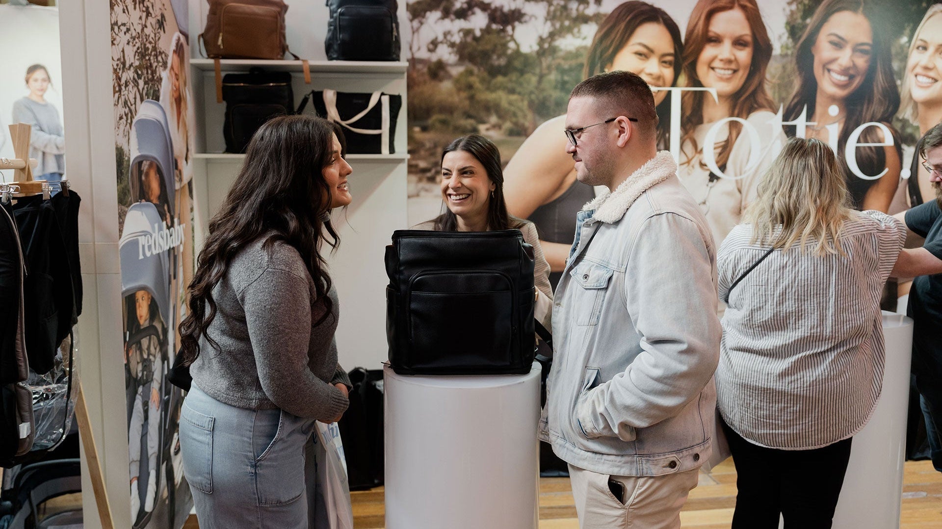 Black Friday Australia shopping scene featuring Tottie bags, new mum and dad, and sales staff at the booth.