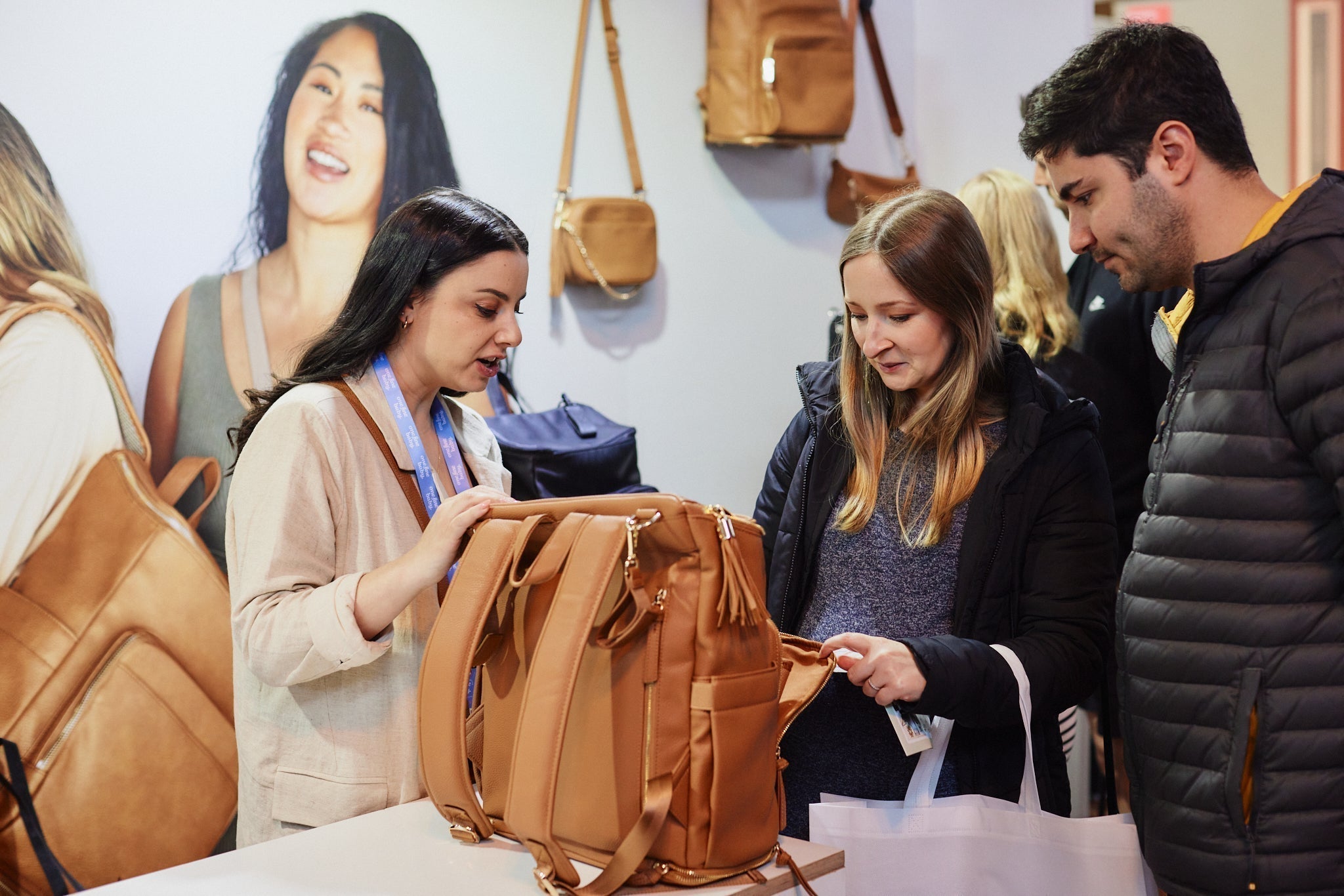 One woman exhibitor showing nappy bags to two visitors at a baby expo in Australia.