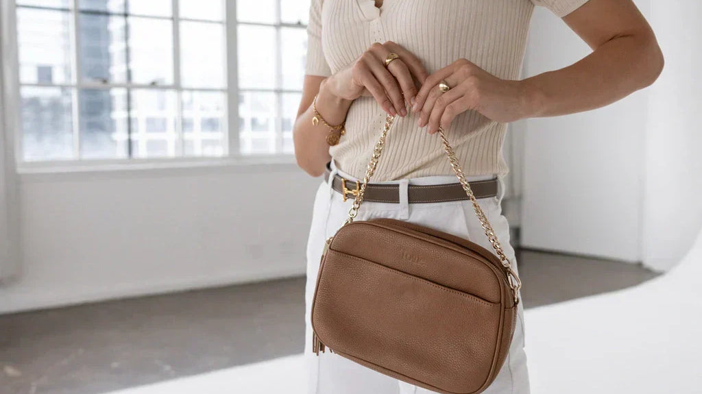 Woman in smart casual at an office holding a brown crossbody bag for work and weekends