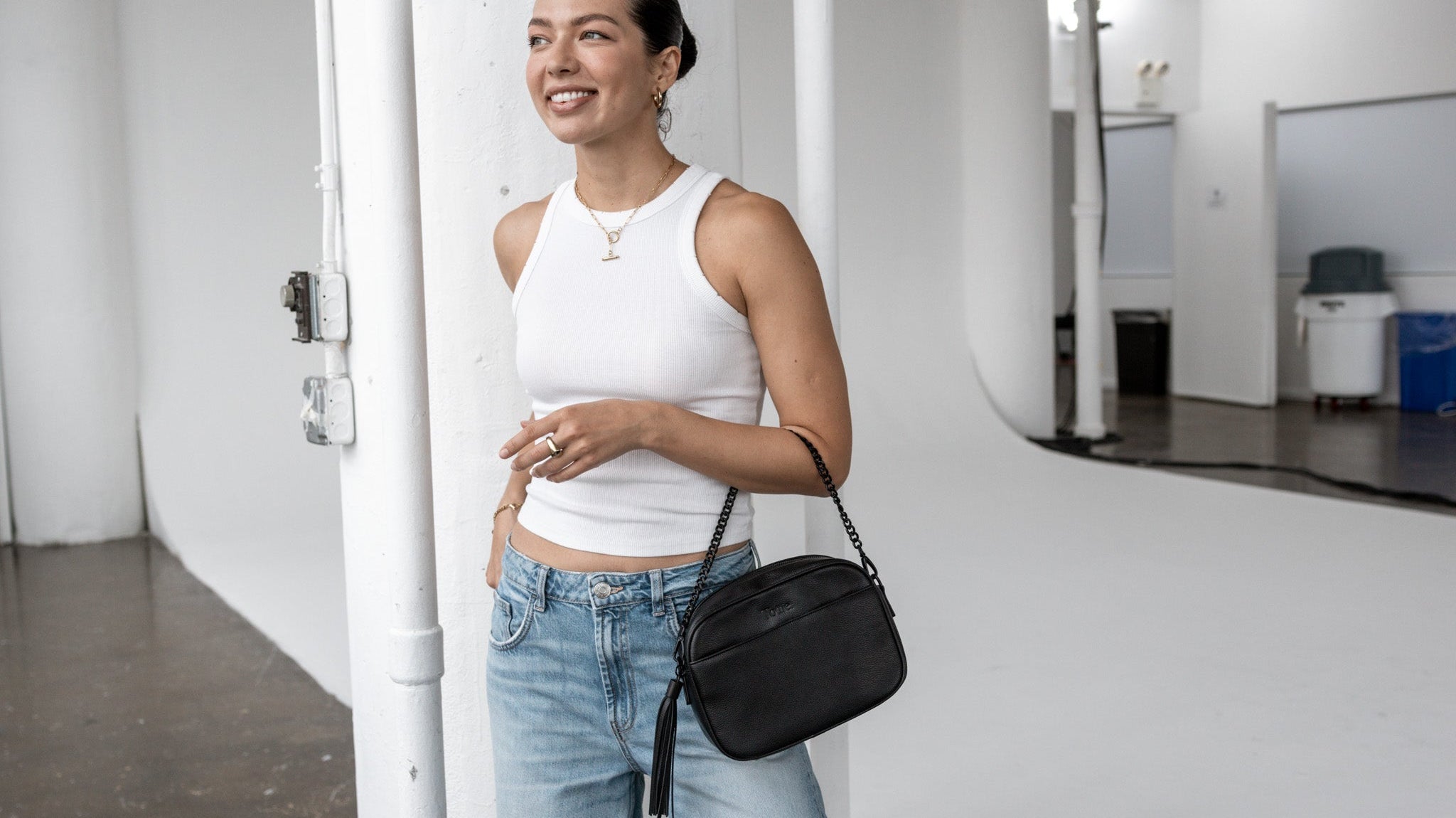 Fashionable black crossbody bag on a woman wearing a white sleeveless top – versatile for day-to-day wear.