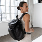 Woman seen from the side wearing a functional nappy bag backpack with black hardware.