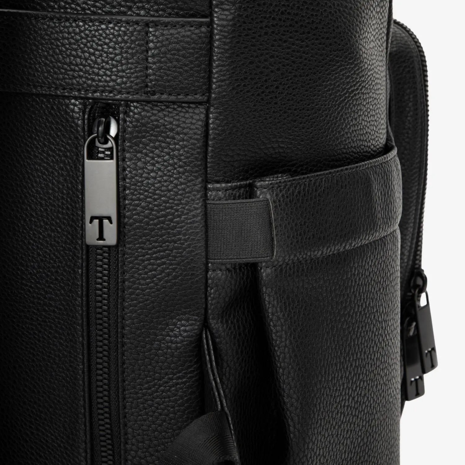 Close-up of the zipper and insulated bottle compartment of a black nappy bag backpack with black hardware, shown on a white background.