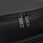 Detailed view of T-shaped zipper pull on black nappy bag backpack with black hardware against white background