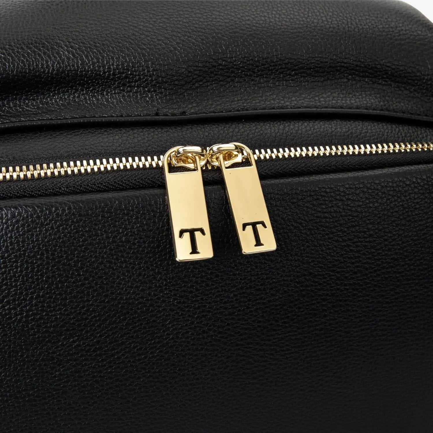 Elegant gold zipper with letter T on black nappy bag backpack – close-up of signature hardware detail.