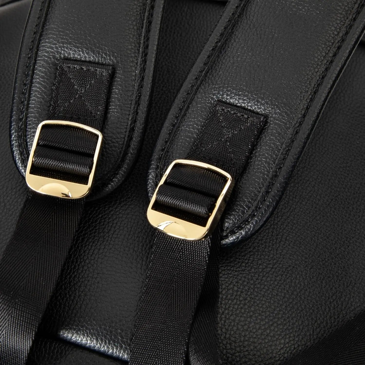 Detailed view of black nappy bag backpack strap featuring gold hardware – elegant and practical design.