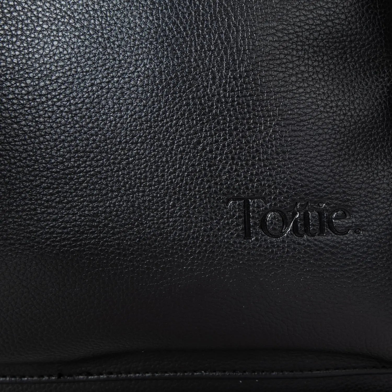 Embossed Tottie branding on black nappy bag backpack with silver hardware – sleek and subtle designer touch.