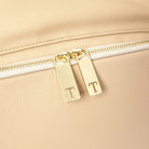 Detailed view of gold Tottie zipper with T emblem on stone colour nappy bag backpack – stylish and functional accent.