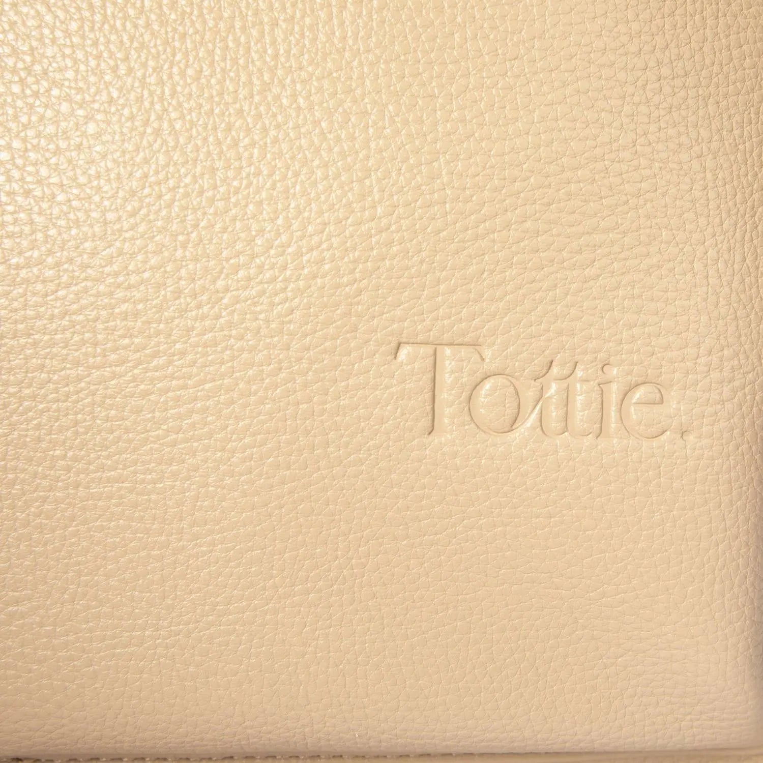 Detailed view of Tottie logo embossed on stone colour nappy bag backpack with gold hardware – elegant brand touch