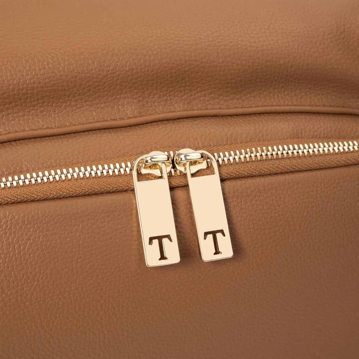Close-up of zipper with letter T on tan nappy bag backpack with gold hardware – branded detail