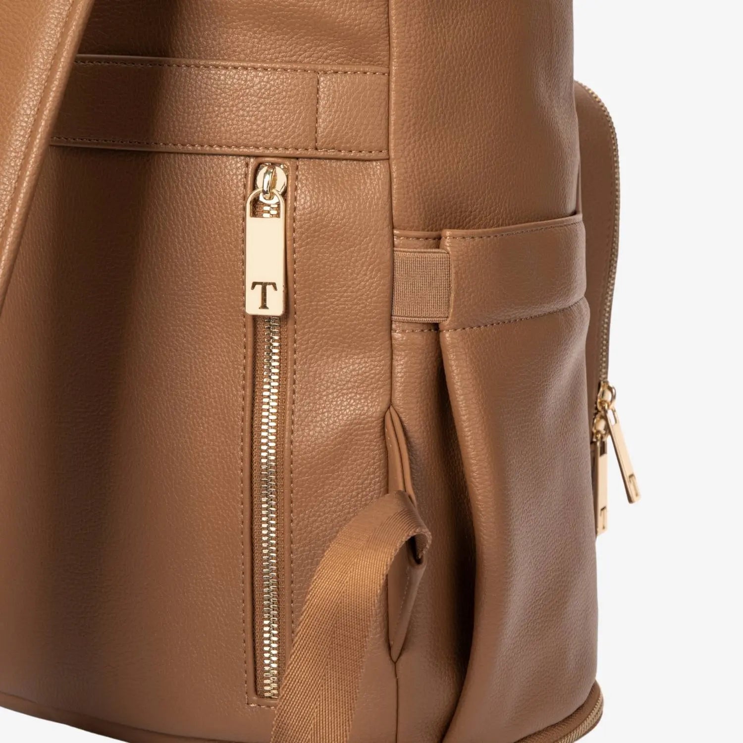 Side view close-up of tan nappy bag backpack zipper with gold hardware – smooth and durable finish.