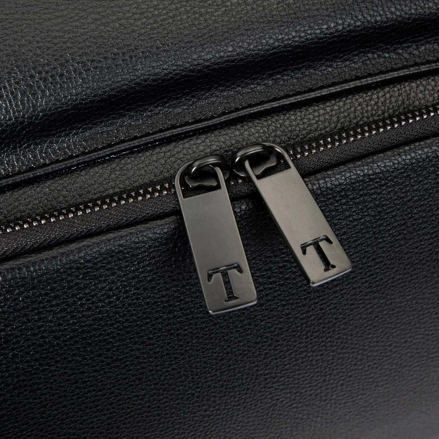 Branded zipper pull with letter T on black nappy bag backpack with black hardware – elegant finishing touch.
