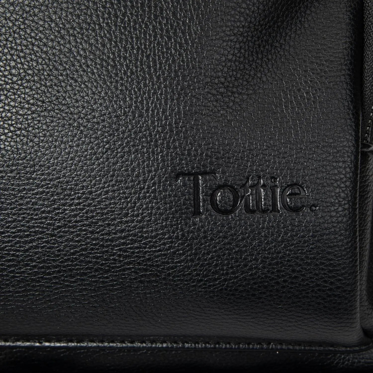 Embossed Tottie logo close-up on black colour nappy bag backpack with black hardware
