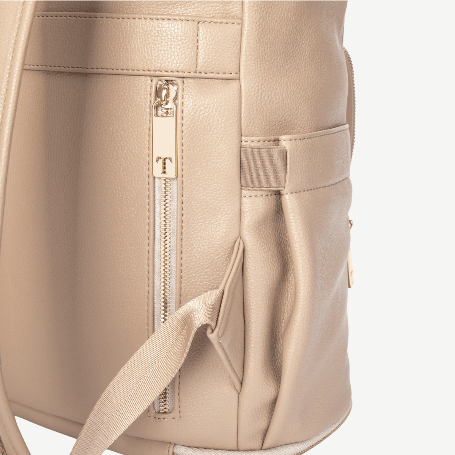 Close-up of a beige travel backpack with a zipper and brand logo.