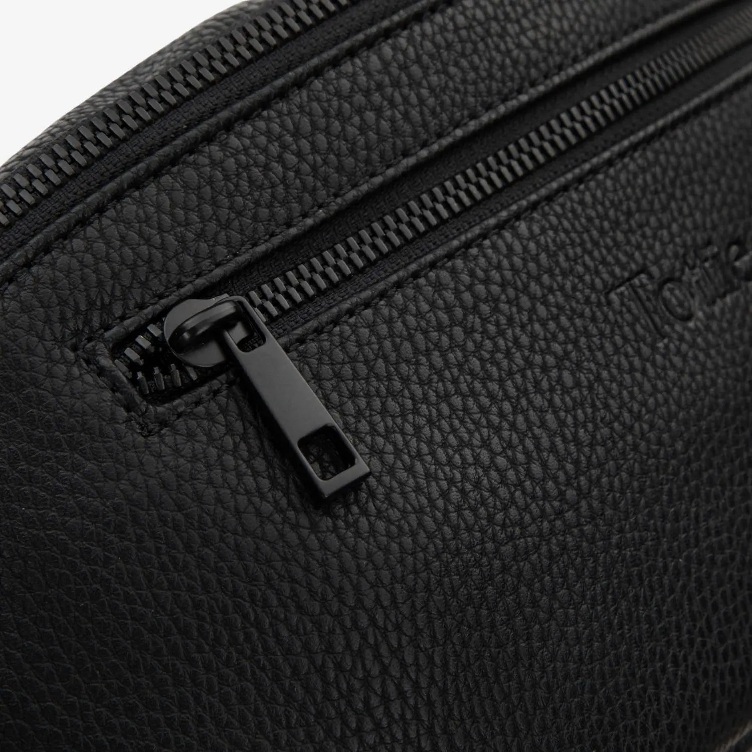 Detailed view of black zipper on black bum bag, highlighting durable construction.