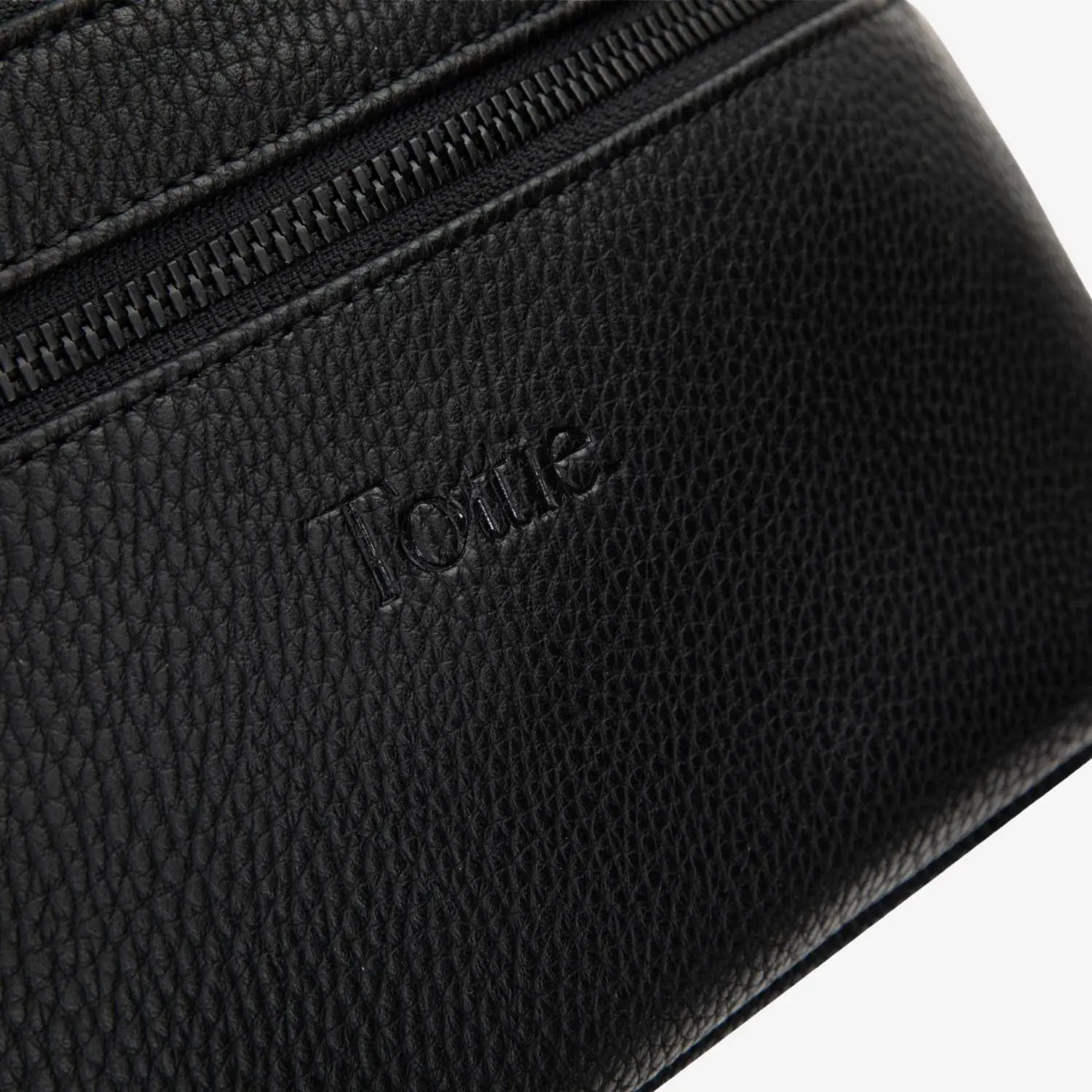 Embossed Tottie logo on sleek black bum bag with tone-on-tone black hardware, against white background