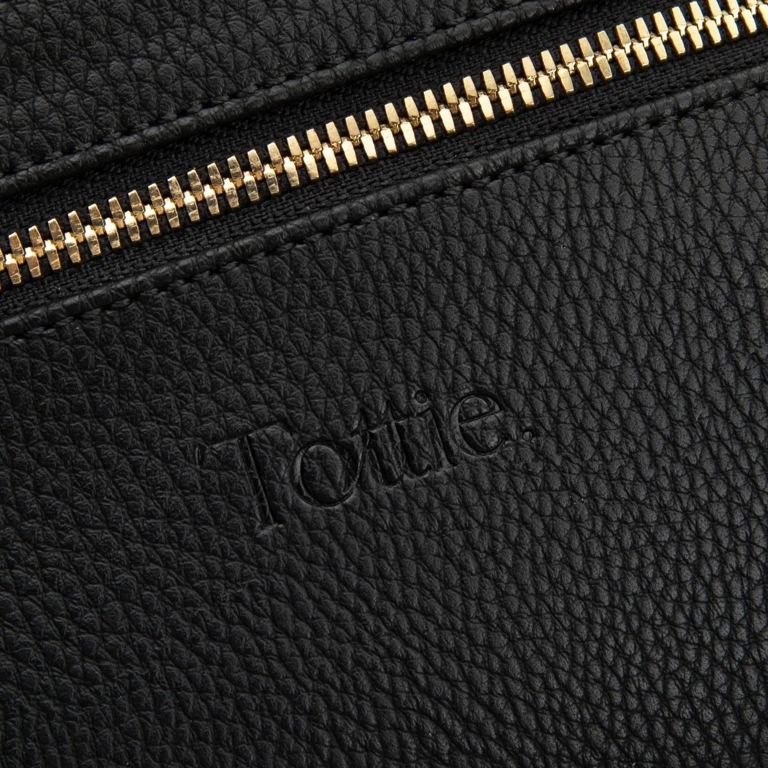 Close-up of Tottie logo embossed on black bum bag with gold hardware – premium branding in every detail.