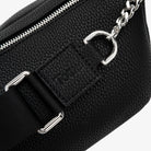 Close-up of black bum bag strap featuring silver hardware and embossed Tottie logo – durable and stylish detail.
