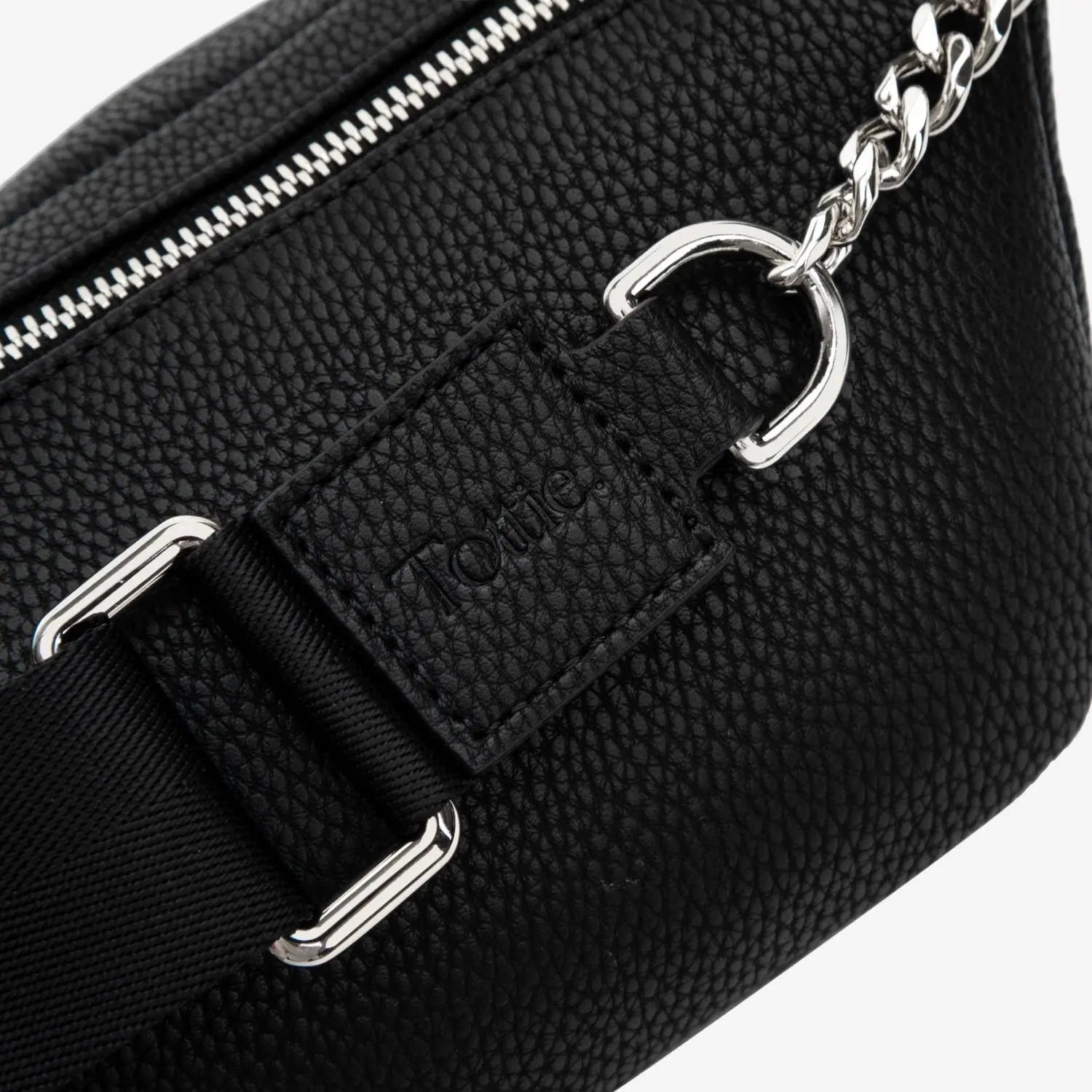 Close-up of black bum bag strap featuring silver hardware and embossed Tottie logo – durable and stylish detail.
