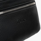 Tottie logo embossed on black bum bag close-up with polished silver hardware accents.