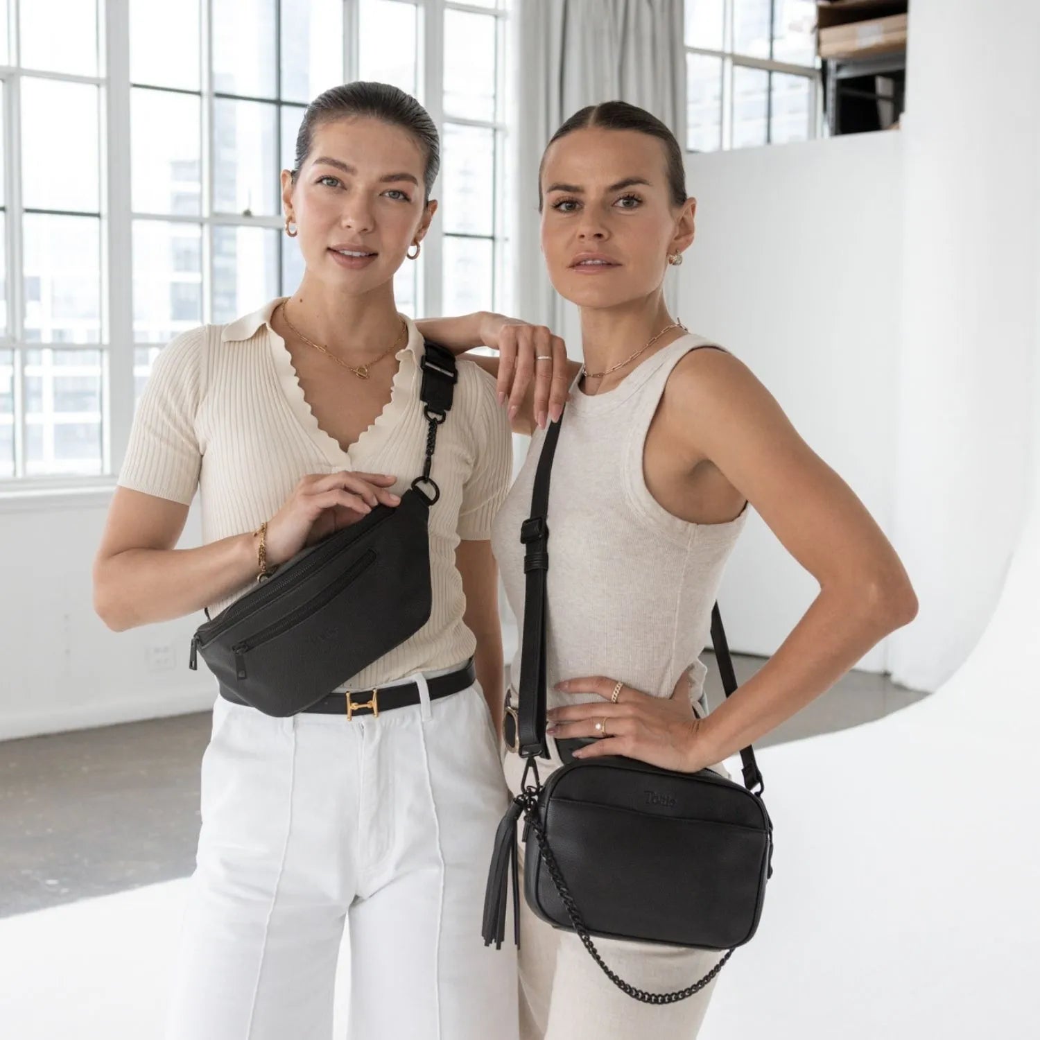 Stylish women showcasing black accessories – black bum bag and black crossbody bag, both with matching black hardware