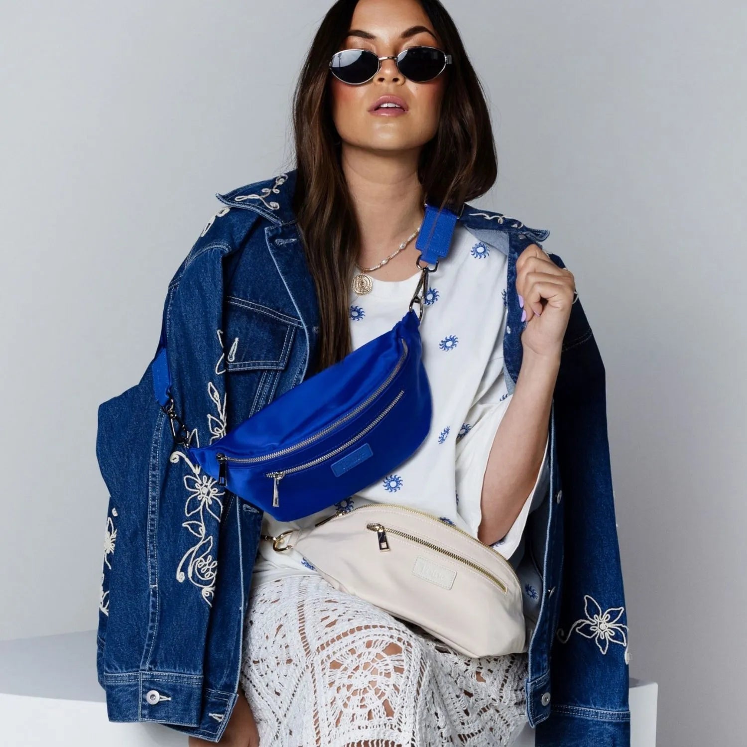 Fashionable woman with royal blue nylon bum bag and cream nylon bum bag.