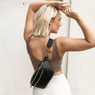 Stylish woman wearing a black bum bag with silver hardware crossbody on her back, perfect for everyday use