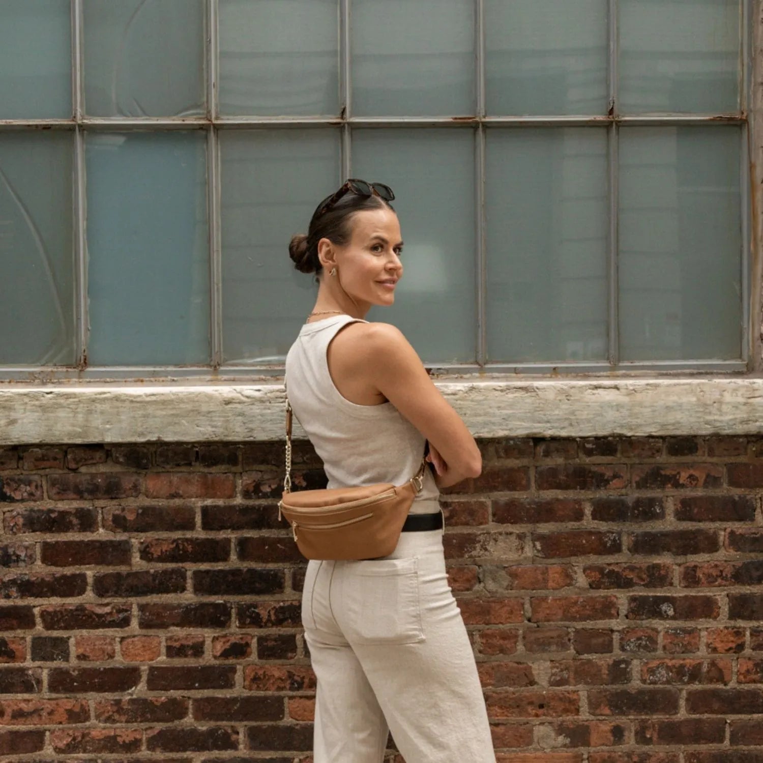 Woman wearing a tan bum bag in crossbody style, positioned on her back for a hands-free look.