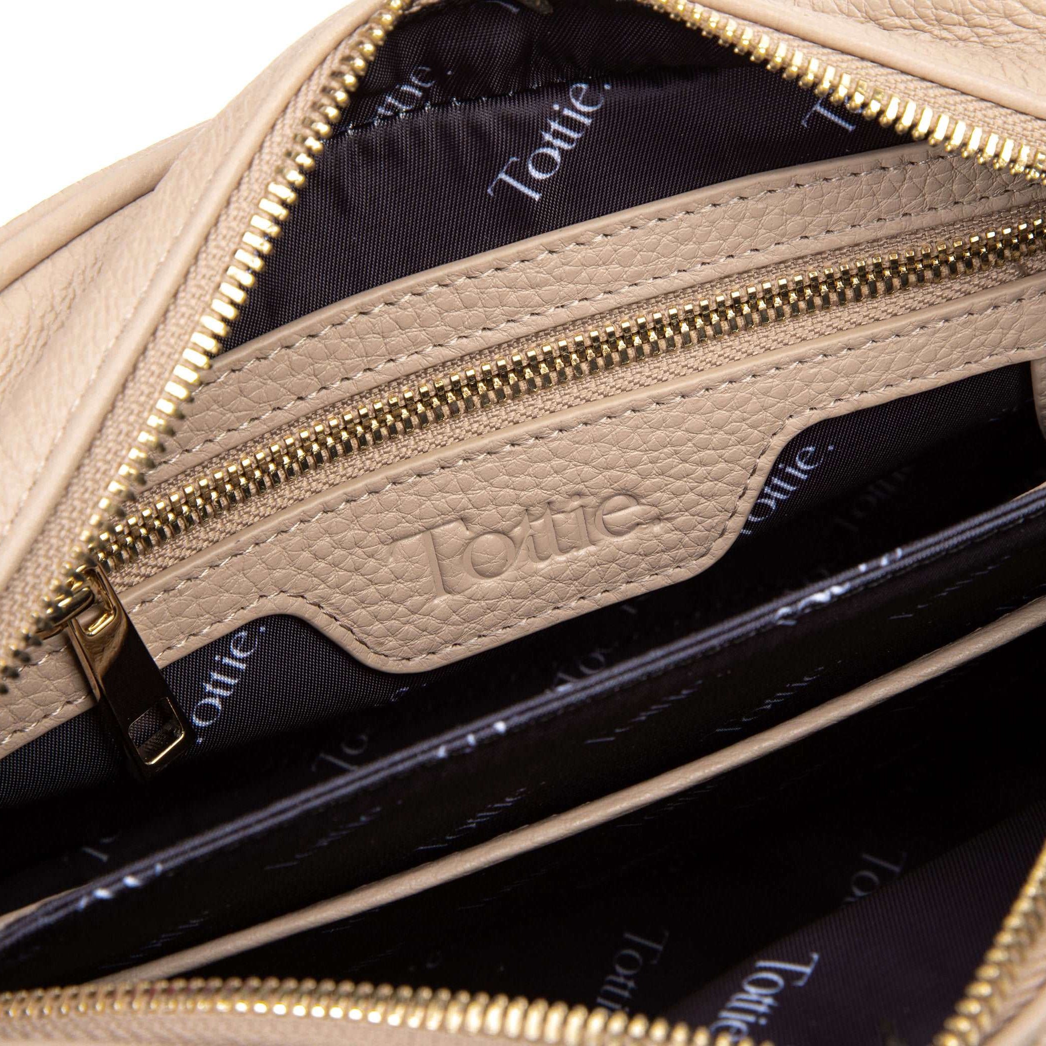 unzipped stone colored leather crossbody bag in white background