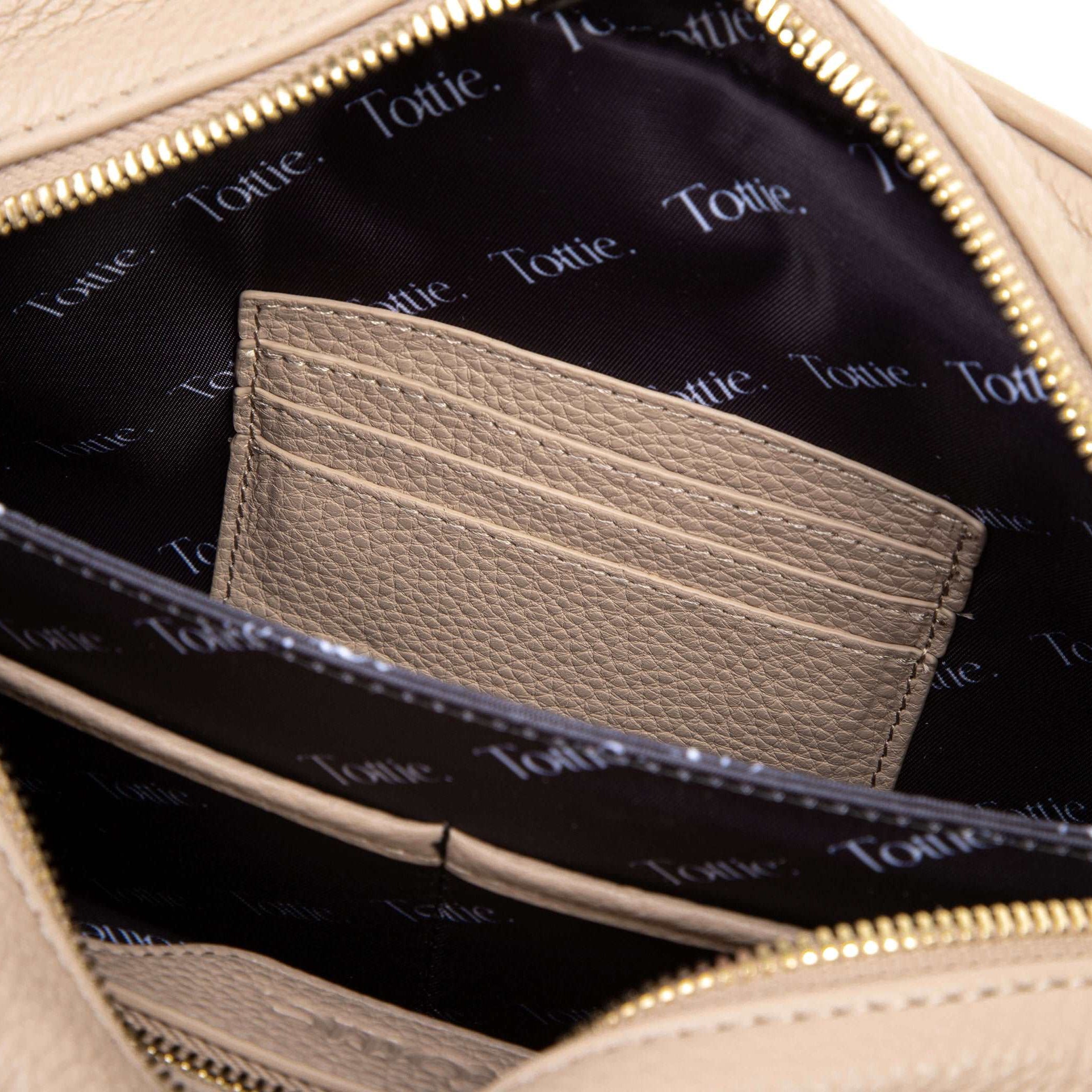 unzipped stone colored leather crossbody bag in white background