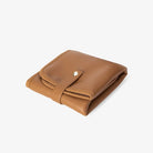 Folded tan change mat with stylish gold hardware – practical and modern essential for organised parents