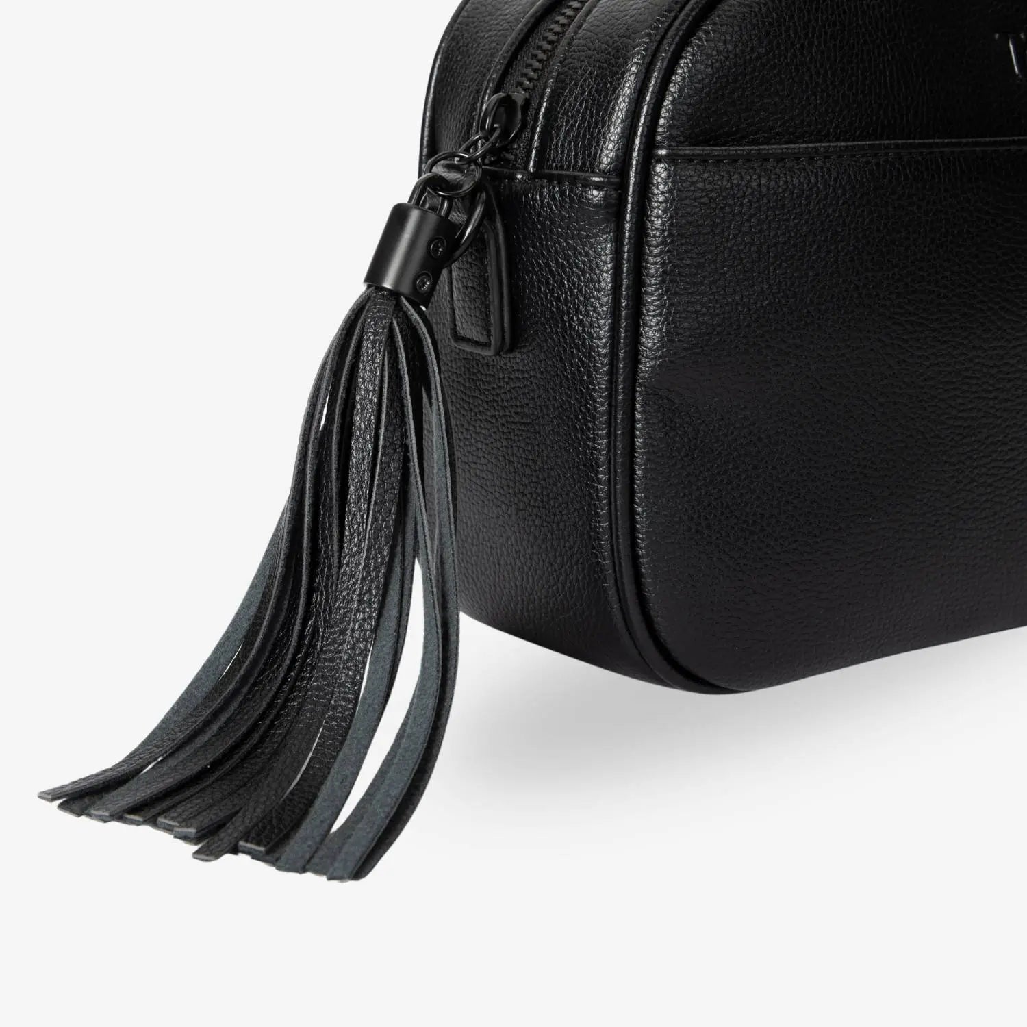Close-up of black tassel detail on black crossbody bag – stylish and subtle accessory accent.