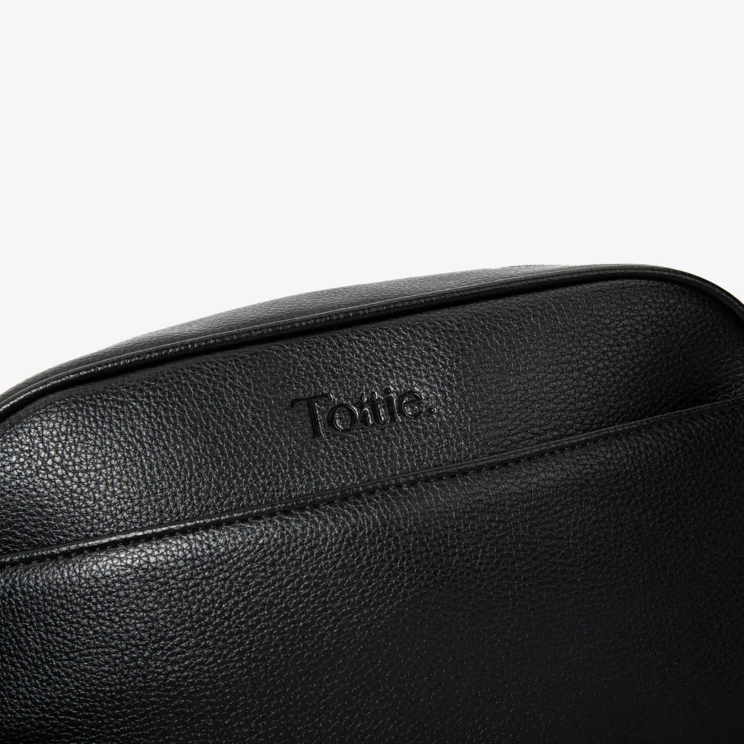 Embossed Tottie logo on black crossbody bag with matching black hardware – detailed shot on white background.