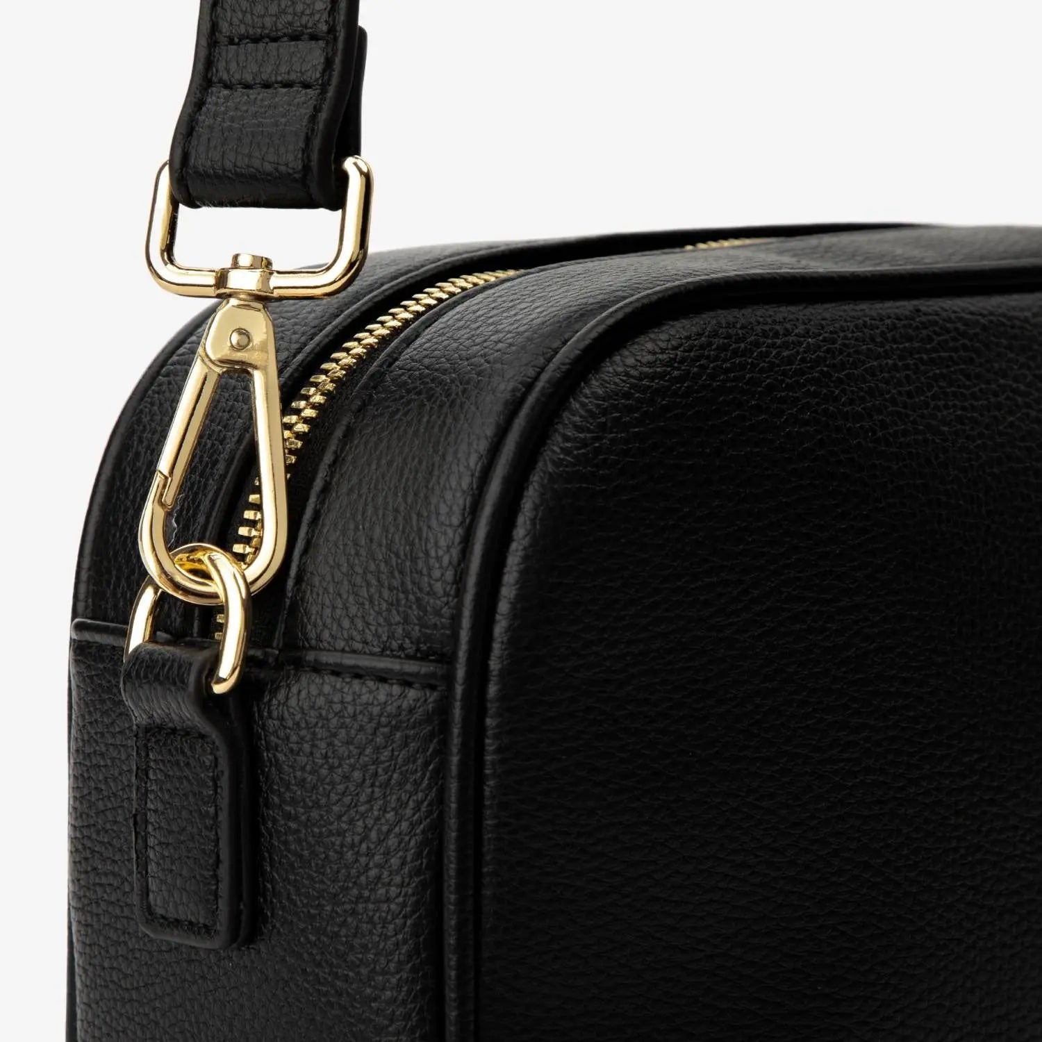Detailed view of gold-tone hardware connecting black strap on black crossbody bag.