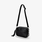 Black crossbody bag shown from a slight side angle featuring silver-tone hardware.