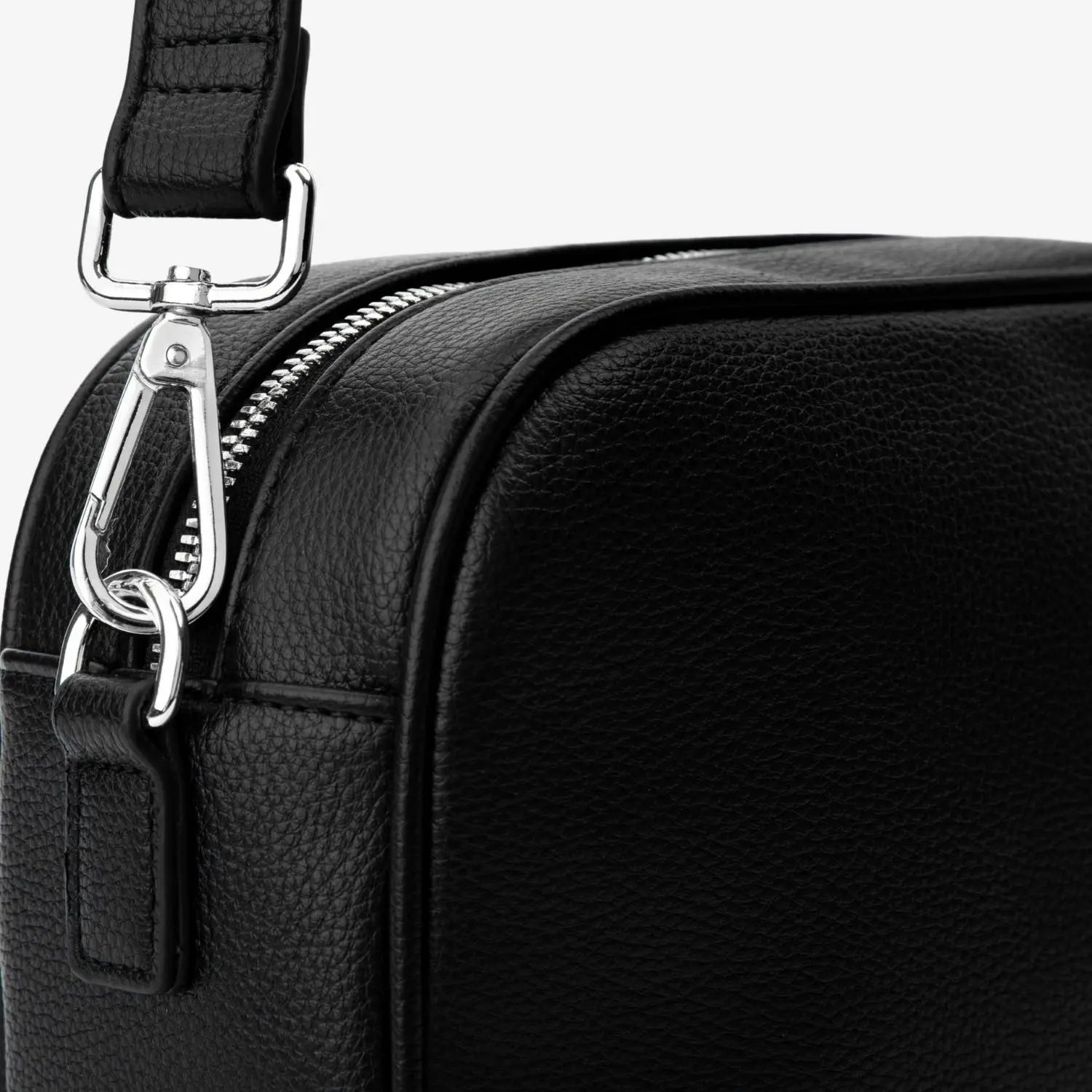 Elegant silver hardware fastening the black strap of a black crossbody bag – detailed close-up.