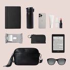 Everyday on-the-go essentials for women with a sleek crossbody bag in black with silver detailing and functional items.
