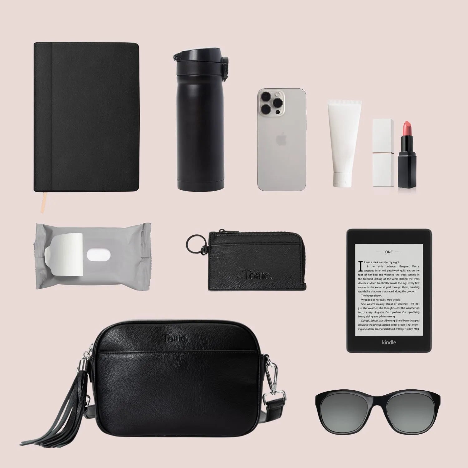 Everyday on-the-go essentials for women with a sleek crossbody bag in black with silver detailing and functional items.