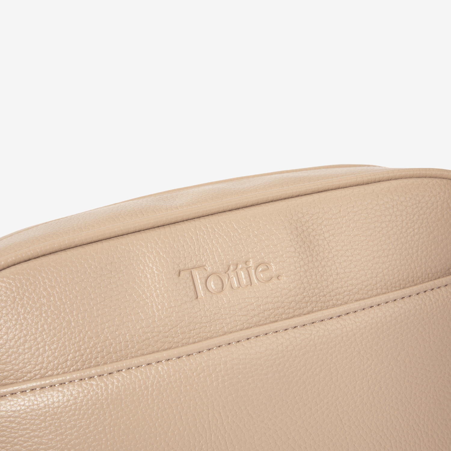 Beige leather crossbody bag with 'Tottie' logo on a light beige background