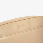 Close-up shot of stone colour crossbody bag with embossed Tottie logo