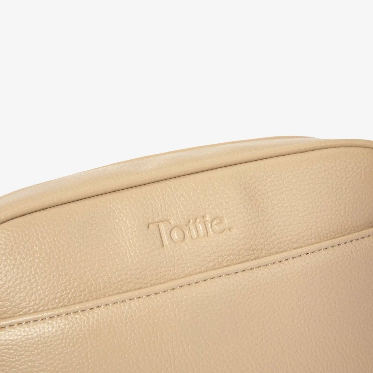 Close-up shot of stone colour crossbody bag with embossed Tottie logo