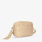 Stone colour crossbody bag with gold hardware captured in a slight side view on clean white background.