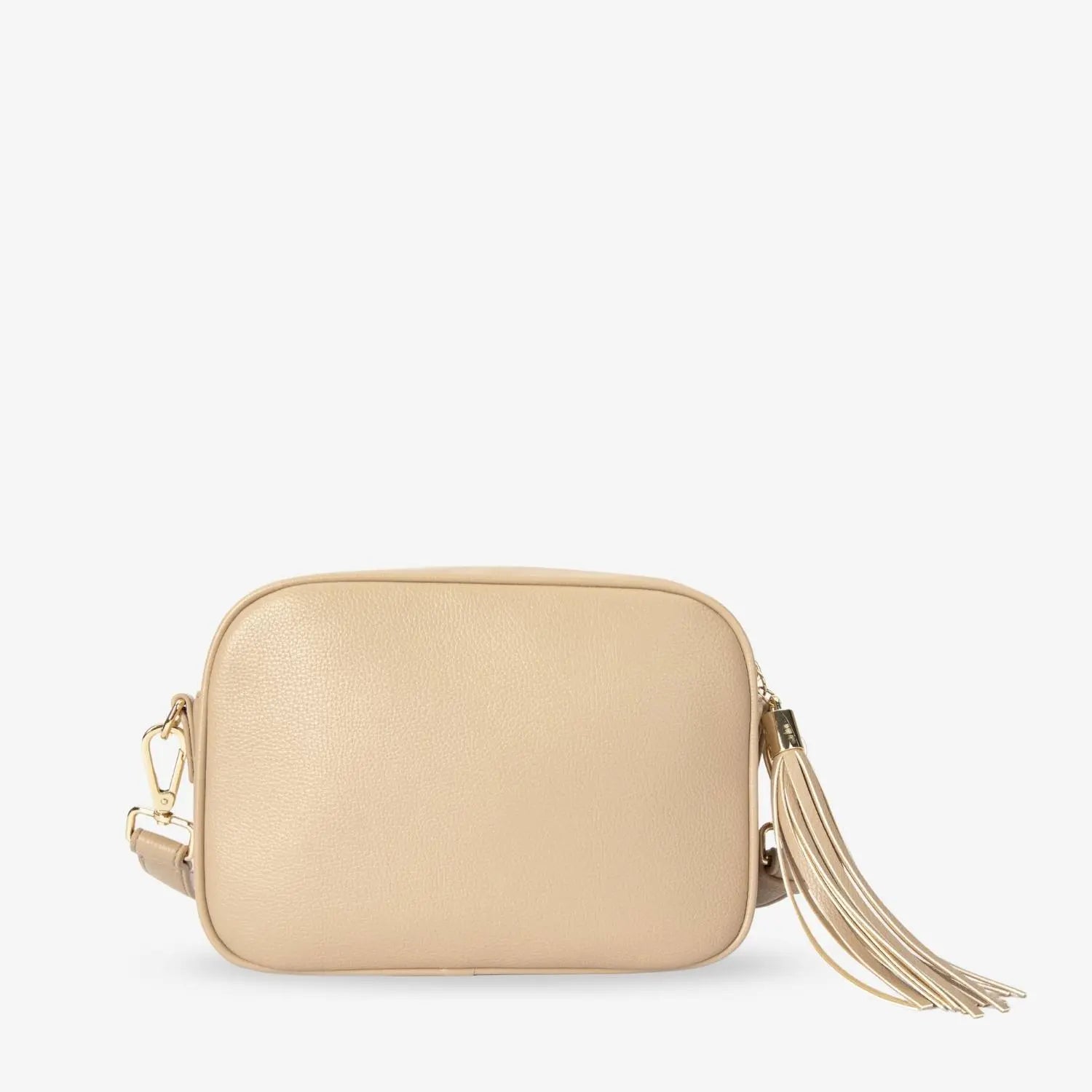 Detailed back shot of stone colour crossbody bag with gold hardware and vegan leather material isolated on white background.