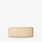 Stone colour crossbody bag’s bottom with gold hardware shown clearly on white background.