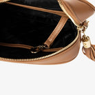 Interior close-up of tan colour crossbody bag showing gold hardware accents.