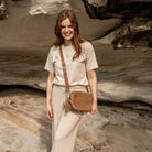 Woman wearing cream terno outfit carrying tan colour crossbody bag with gold hardware.