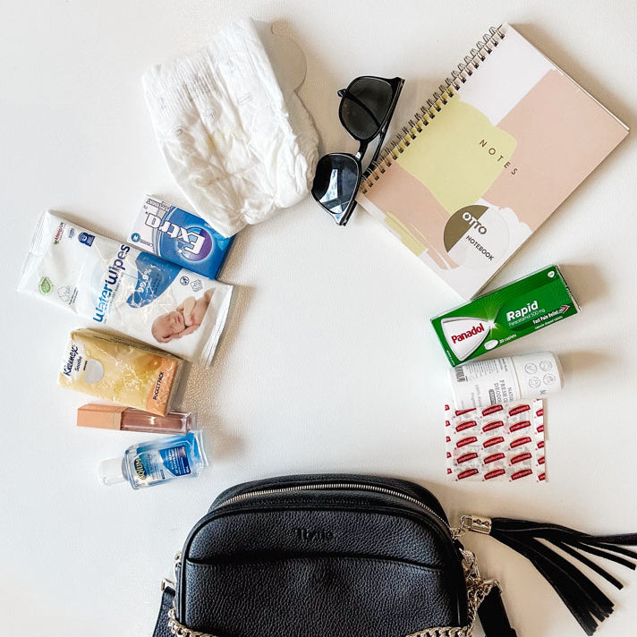 items from a black leather crossbody bag laid out in white background