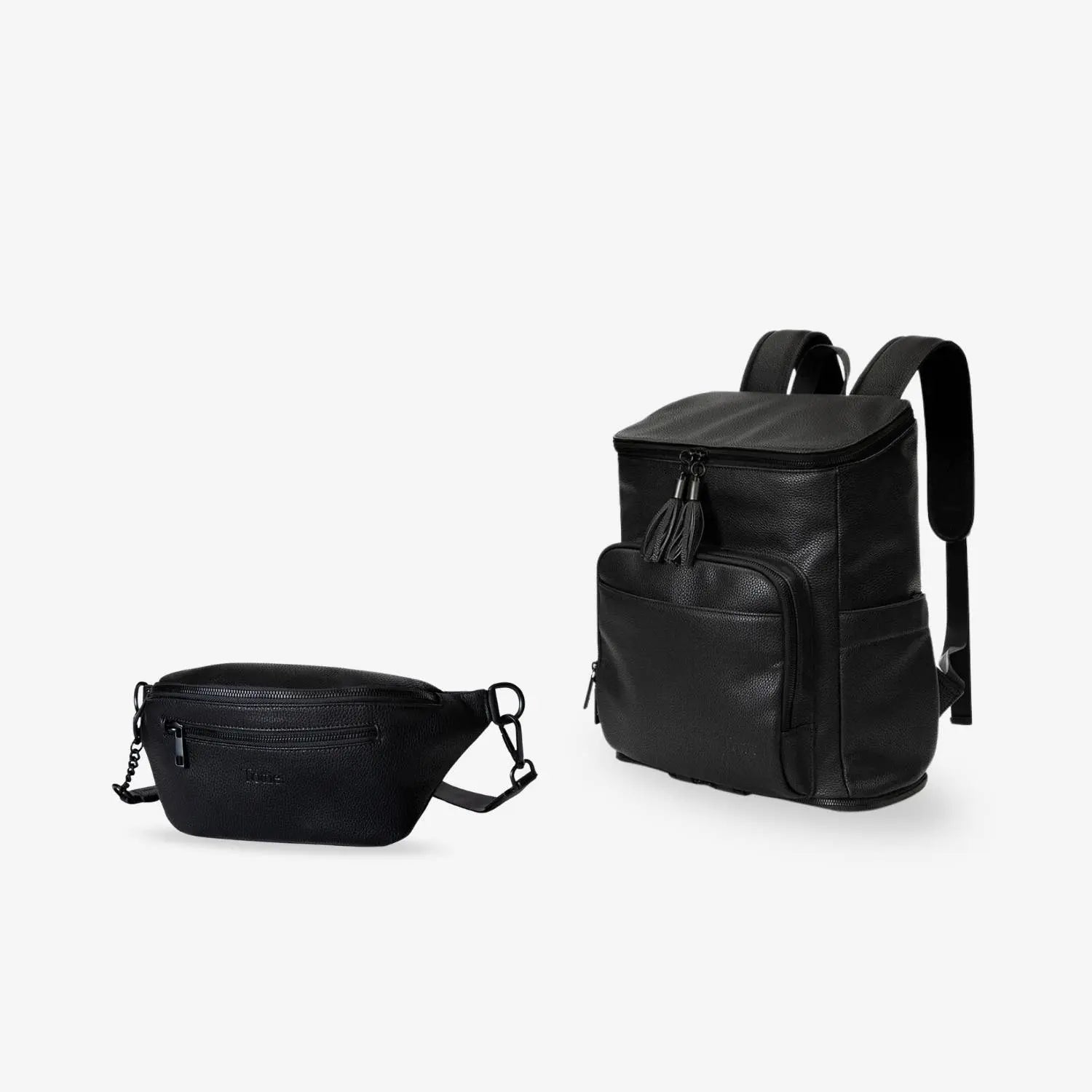 Black nappy bag backpack with black hardware next to a black bum bag with black hardware on white background.