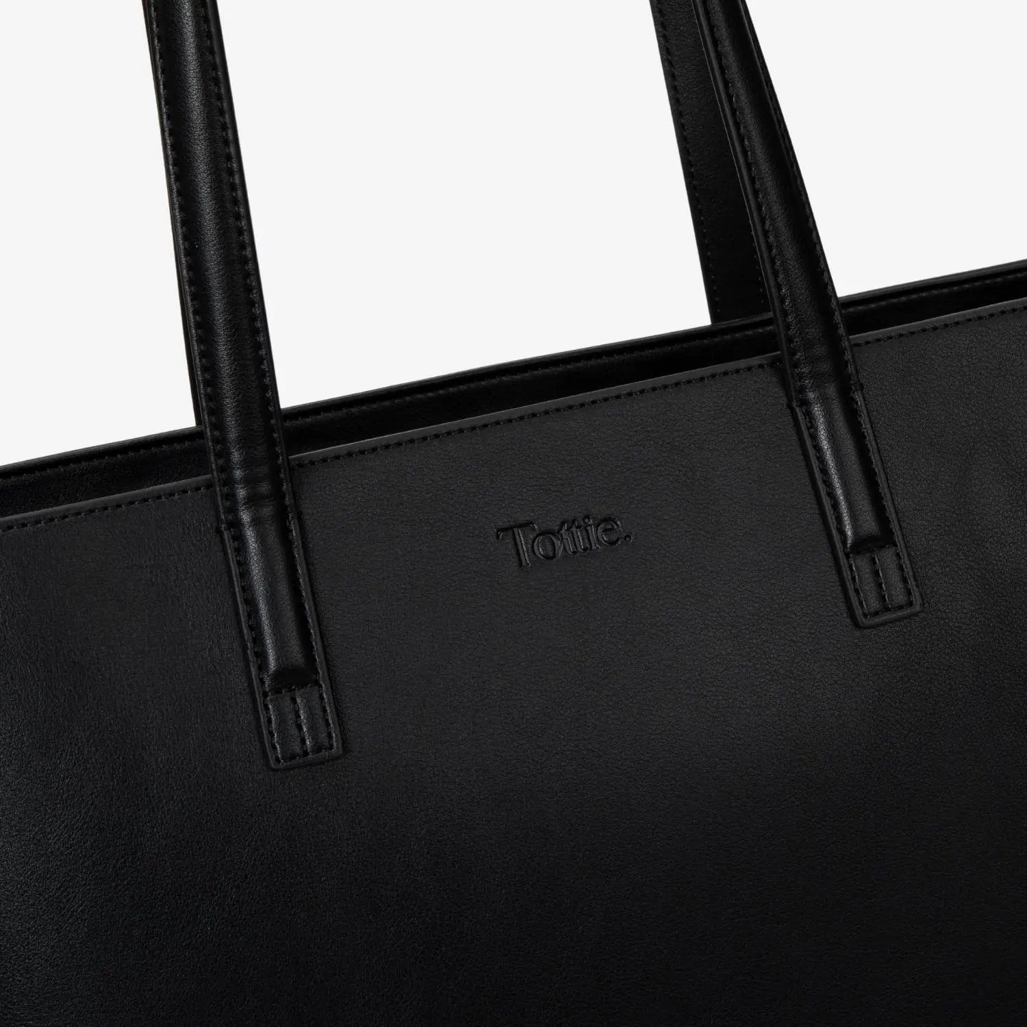Detailed close view of Tottie logo embossed on black tote bag with textured surface.