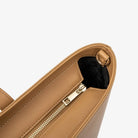 Close view of sturdy zipper on tan tote bag highlighting design and durability.