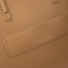 Zoomed-in view of tan tote bag material and structure in natural lighting.